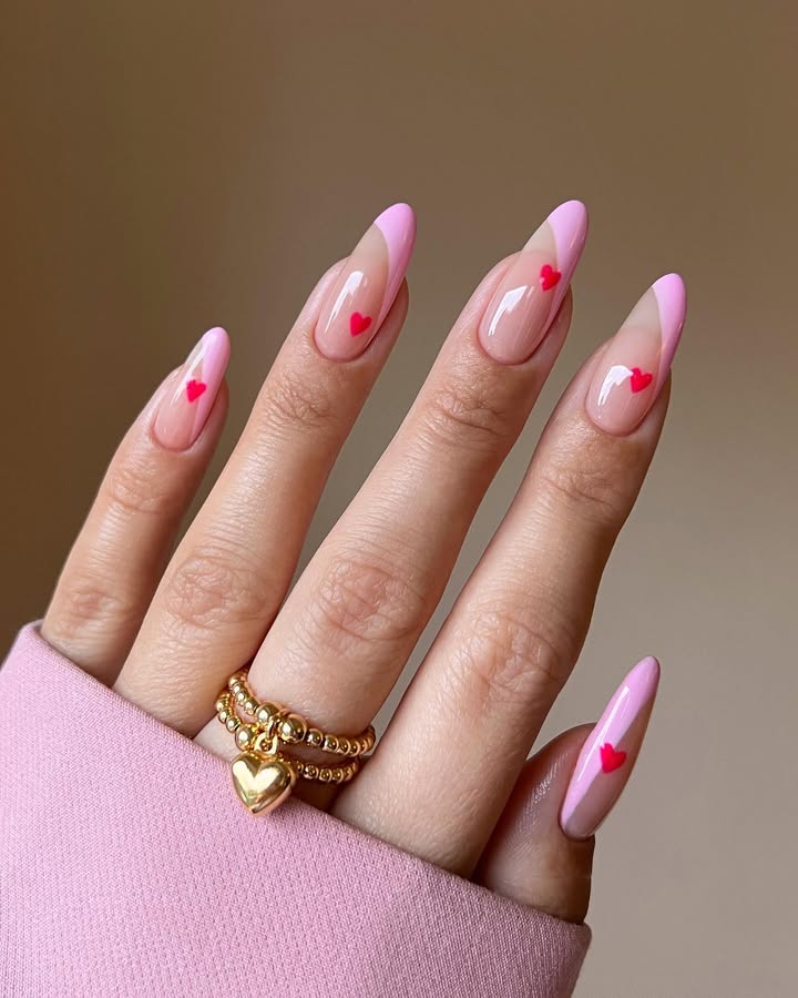 A-hand-with-almond-shaped-pink-French-tip-nails-and-tiny-red-hearts-wearing-a-pink-shirt-and-a-silver-ring.jpg