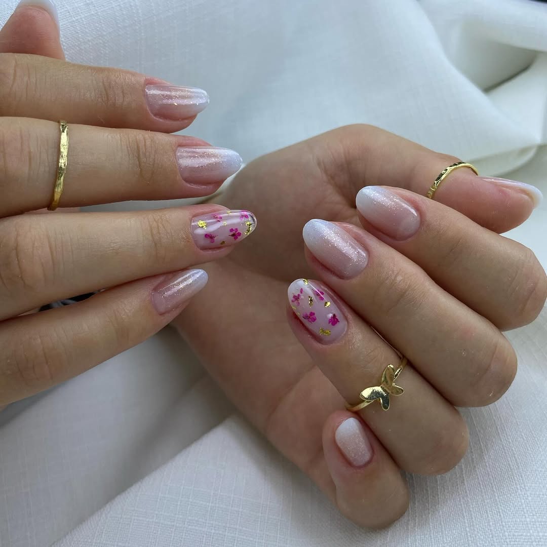 Blossom-ombre-nails-with-soft-pink-pearly-white-floral-details-and-gold-accents-paired-with-golden-rings