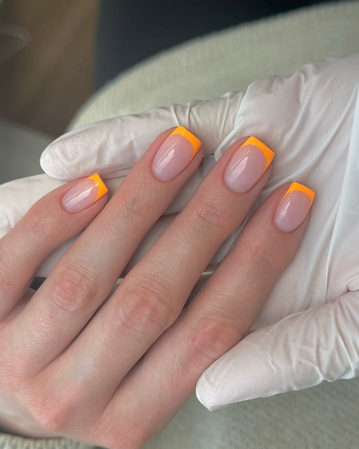 Close-up-of-hand-with-bright-orange-neon-French-tips-perfect-for-a-bold-spring-look.jpg