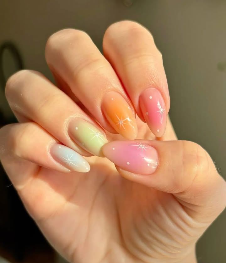 Close-up-of-hand-with-pastel-ombre-spring-nails-featuring-tiny-white-dots-and-starburst-designs.jpg