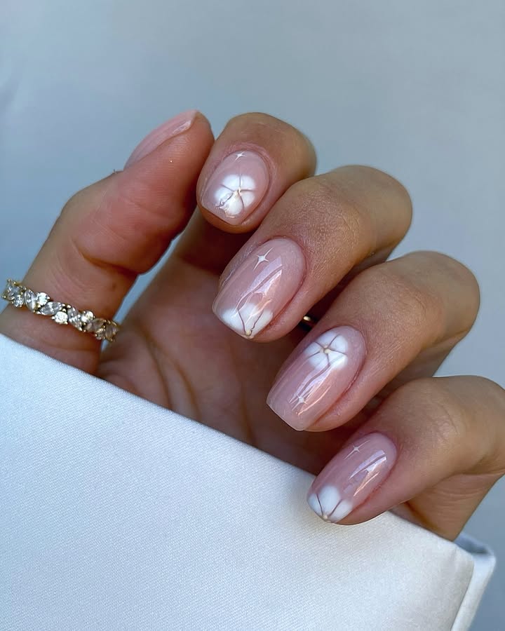Close-up-of-hand-with-peachy-pink-nails-decorated-with-tiny-soft-floral-designs.jpg