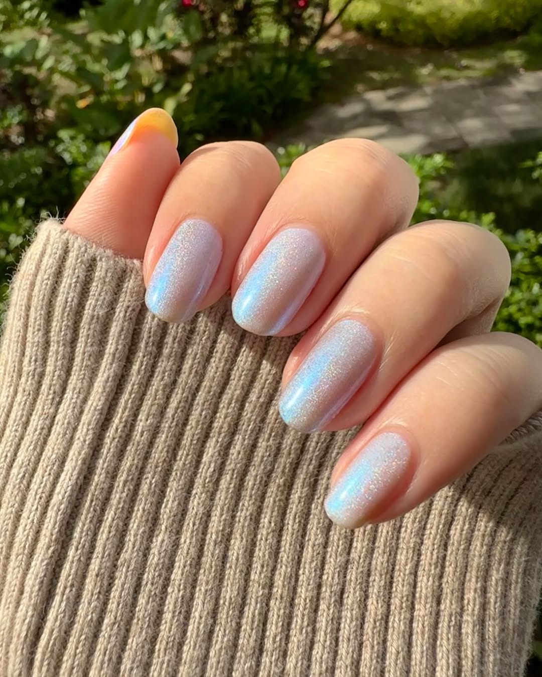 Close-up-of-icy-white-chrome-nails-on-a-hand-dressed-in-a-sweater.