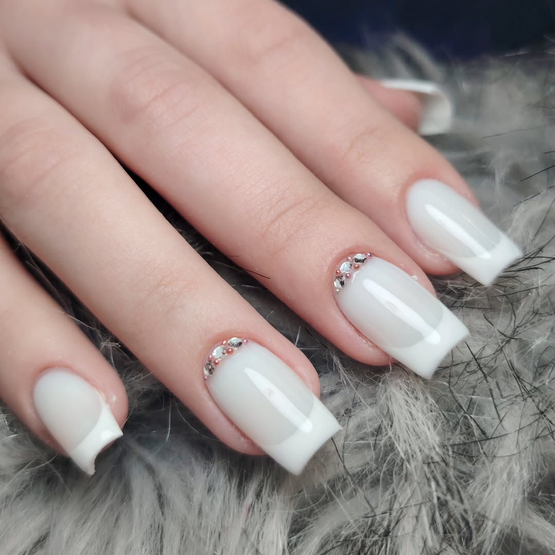 Glossy-white-French-tips-nails-with-rhinestone-accents-on-a-furry-surface.