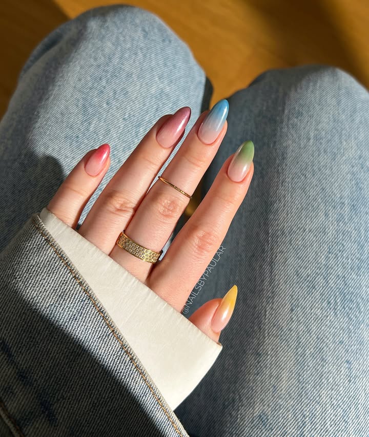 Hand-with-multicolor-ombre-nails-in-pink-purple-blue-green-and-yellow-shades-styled-with-gold-rings-and-denim-outfit.jpg