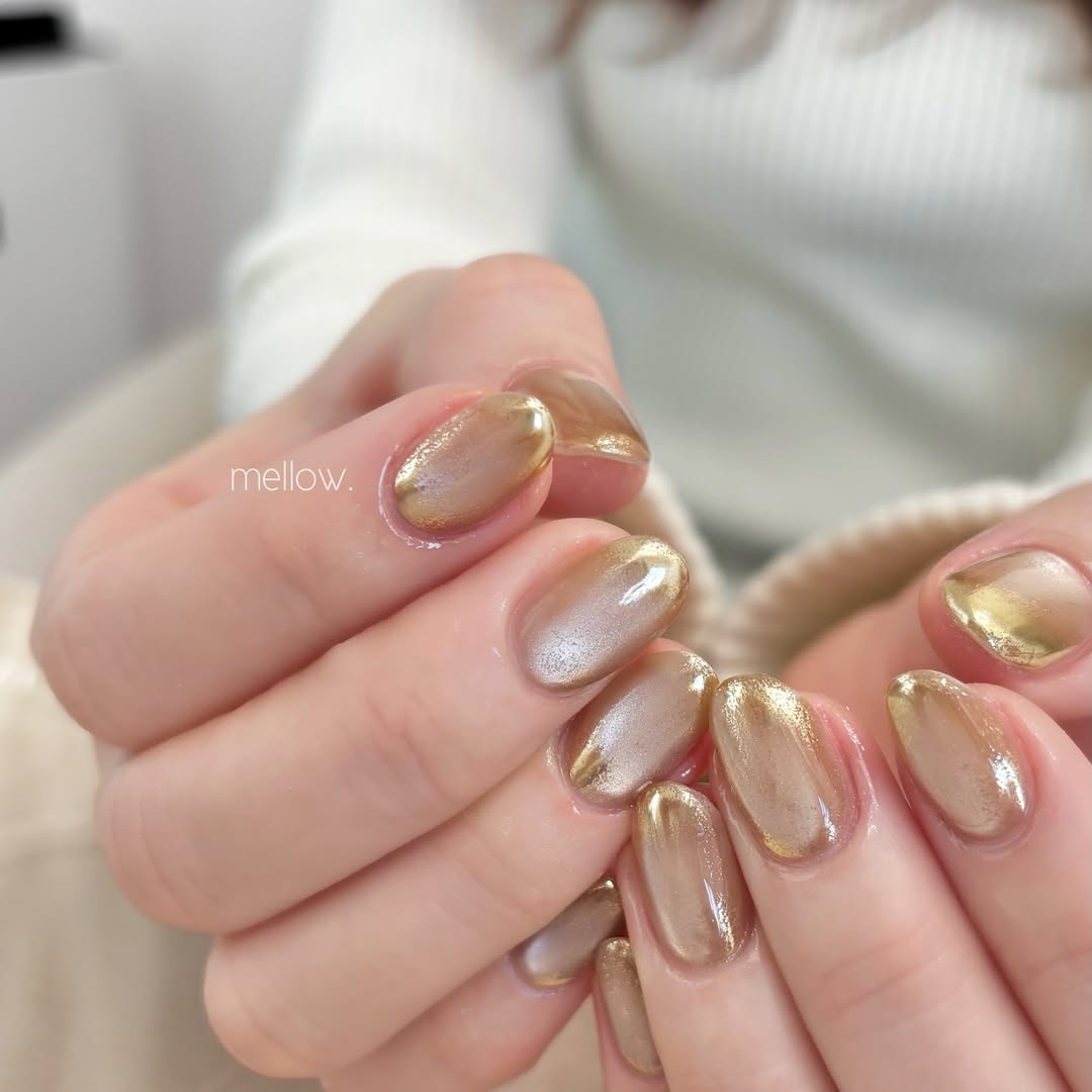 Hands-with-metallic-nail-design-featuring-dark-tips-and-a-gold-shimmer.