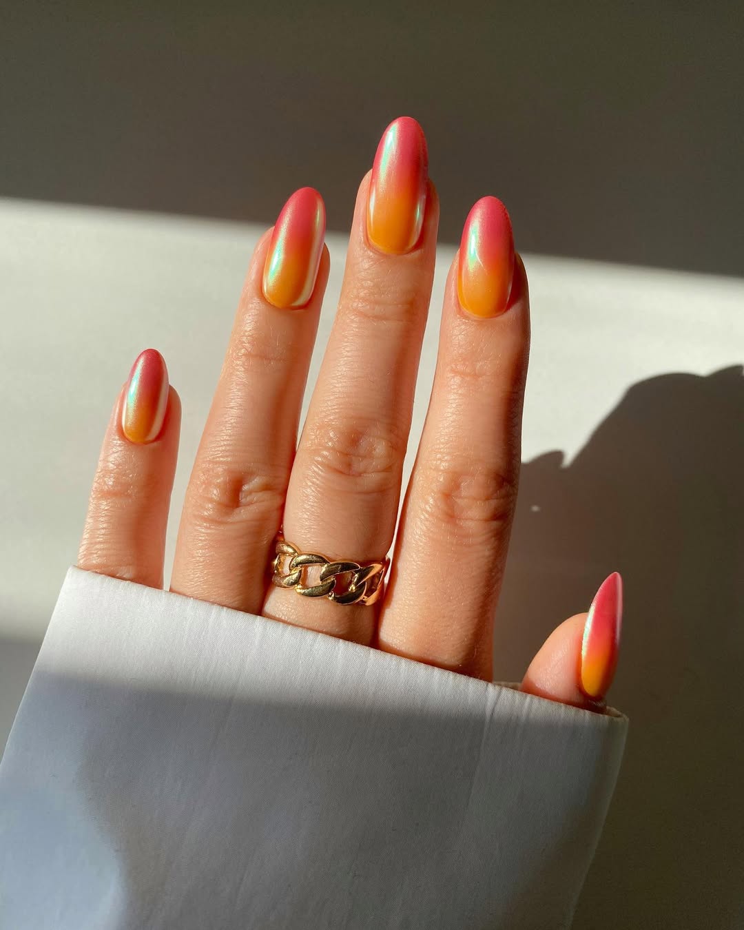 Sunset-glow-ombre-nails-with-a-yellow-to-coral-pink-gradient-and-pearlescent-shine-paired-with-a-ring-and-white-shirt.jpg