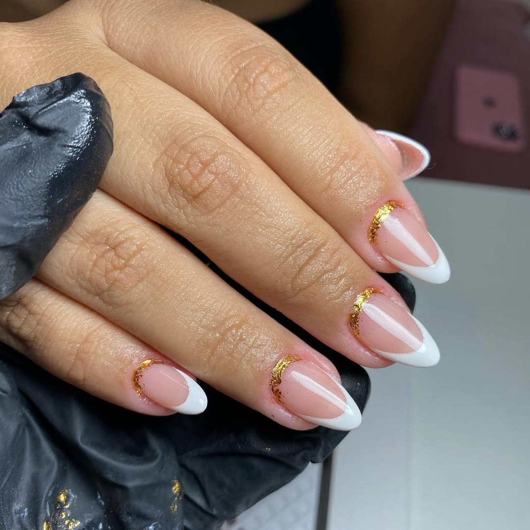 almond-white-french-tip-nails-with-opulent-gold-detailing-on-a-nude-pink-base.