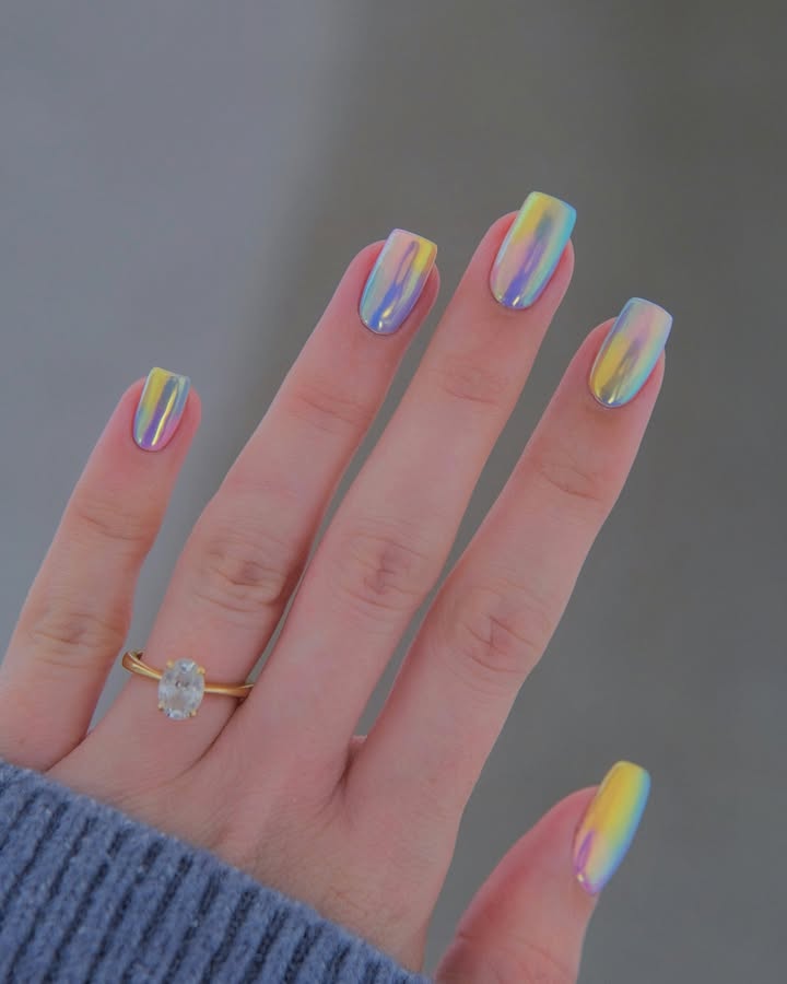Candy-chrome-nails-in-pastel-rainbow-hues-with-a-mirror-like-shine-paired-with-ring-and-blue-shirt.jpg