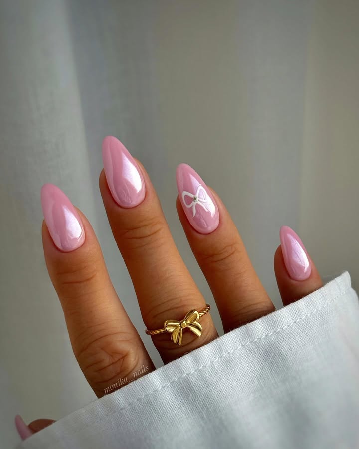 Close-up-of-glossy-pink-Barbie-blush-nails-with-a-single-delicate-bow-charm-accent-paired-with-ring-and-white-shirt.jpg